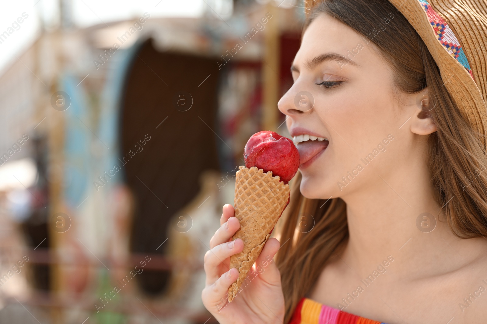 Photo of Young happy woman eating ice cream in amusement park. Space for text