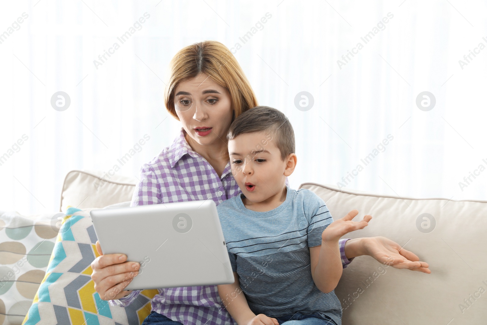 Photo of Mother and her son using video chat on tablet against light background