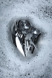 Washing silver spoons, forks and knives in foam, flat lay