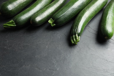 Photo of Green ripe zucchinis on black slate table. Space for text