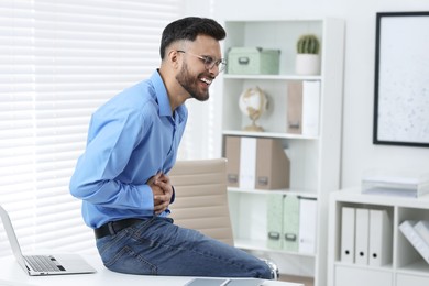 Handsome young man laughing in office, space for text