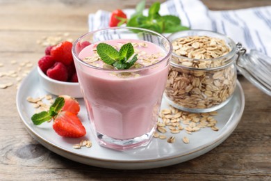 Photo of Glass of tasty berry smoothie with oatmeal on wooden table