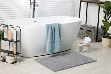 Photo of Stylish bathroom interior with bath tub, houseplants and soft light grey mat