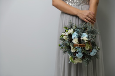 Photo of Bride holding beautiful winter wedding bouquet on light grey background, closeup. Space for text