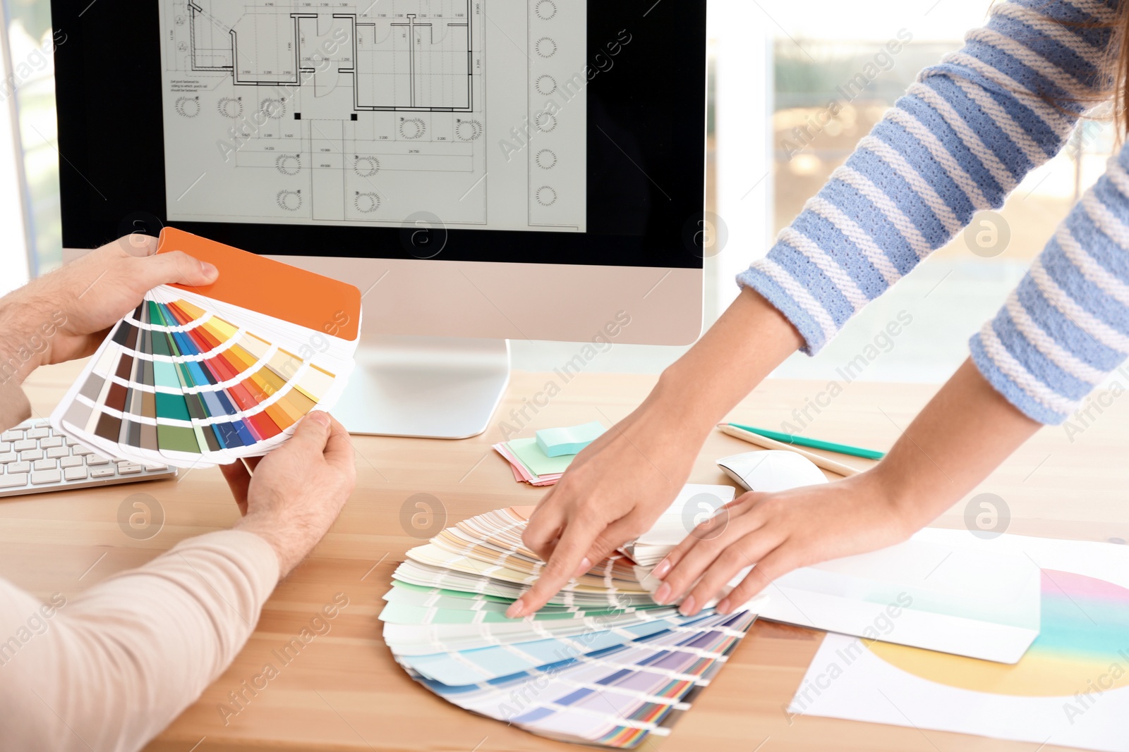 Photo of Designers with paint color palette samples at table, closeup