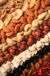 Photo of Different tasty nuts and dried fruits as background, top view