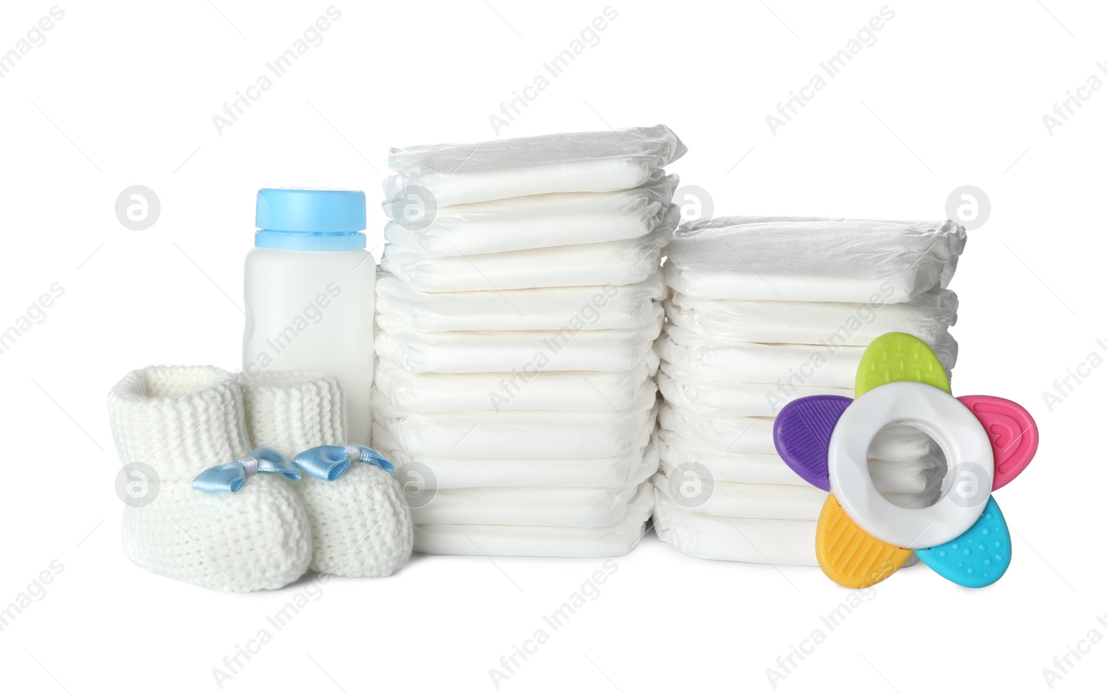 Photo of Disposable diapers, child's booties, teether and bottle on white background