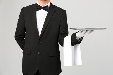 Photo of Waiter holding metal tray on light background