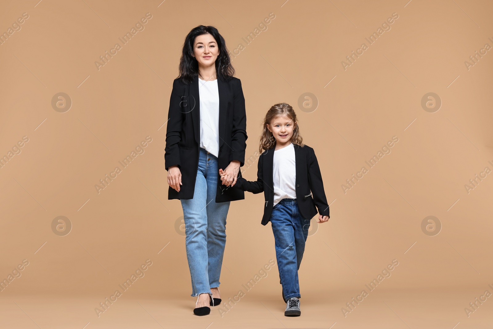 Photo of Beautiful mother with little daughter on beige background