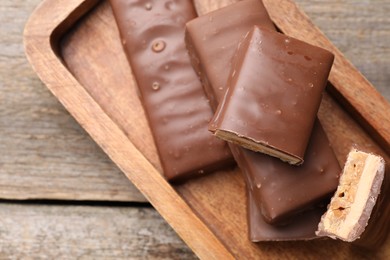 Photo of Tasty chocolate bars with nougat on wooden table, top view