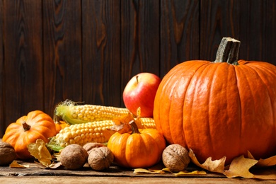 Photo of Composition with vegetables, nuts and autumn leaves on wooden table, space for text. Thanksgiving Day