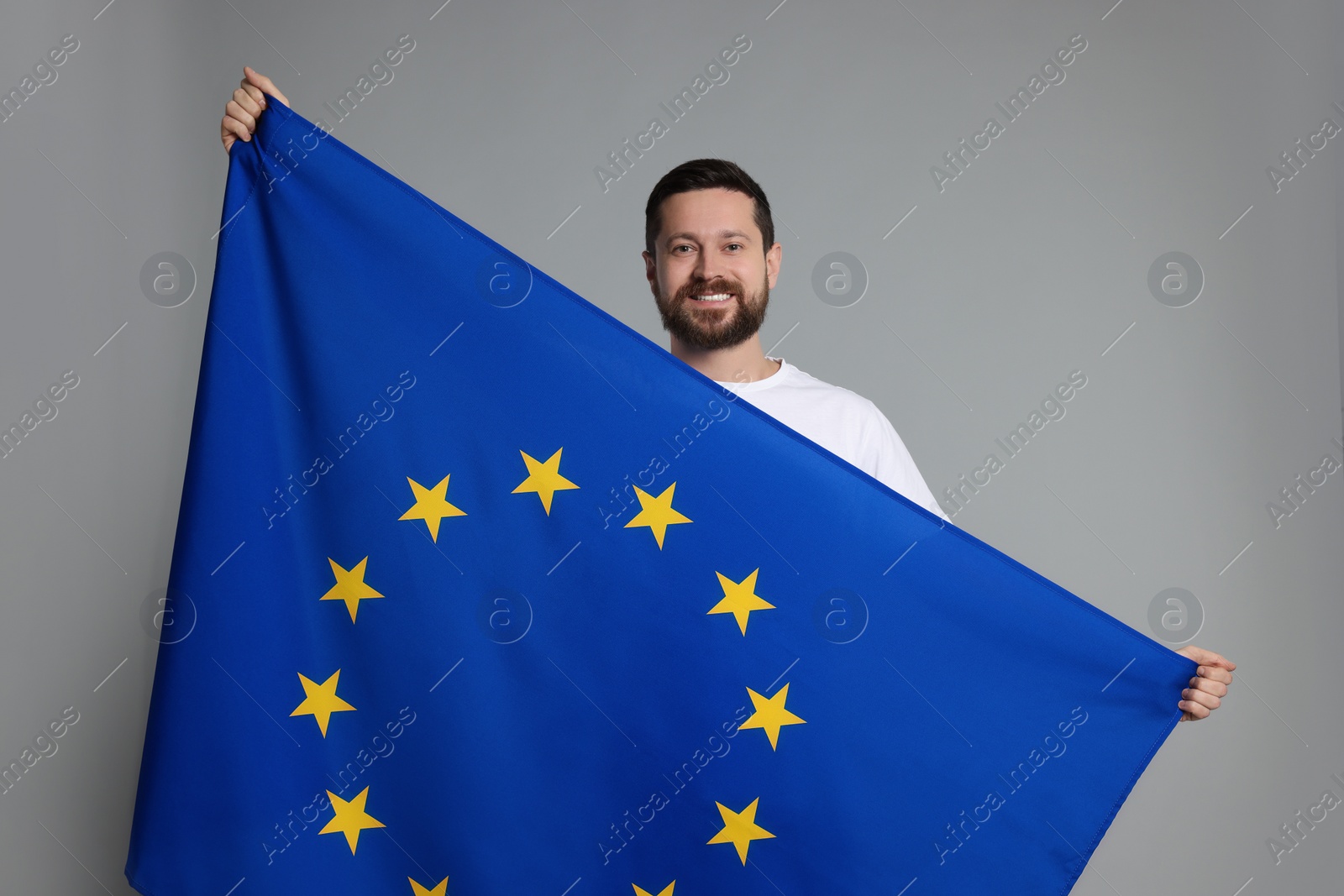 Photo of Man holding European Union flag on light grey background