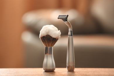 Photo of Shaving brush and razor on table against blurred background