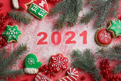 Photo of Flat lay composition with and number 2021 made of flour and tasty homemade Christmas cookies on red background