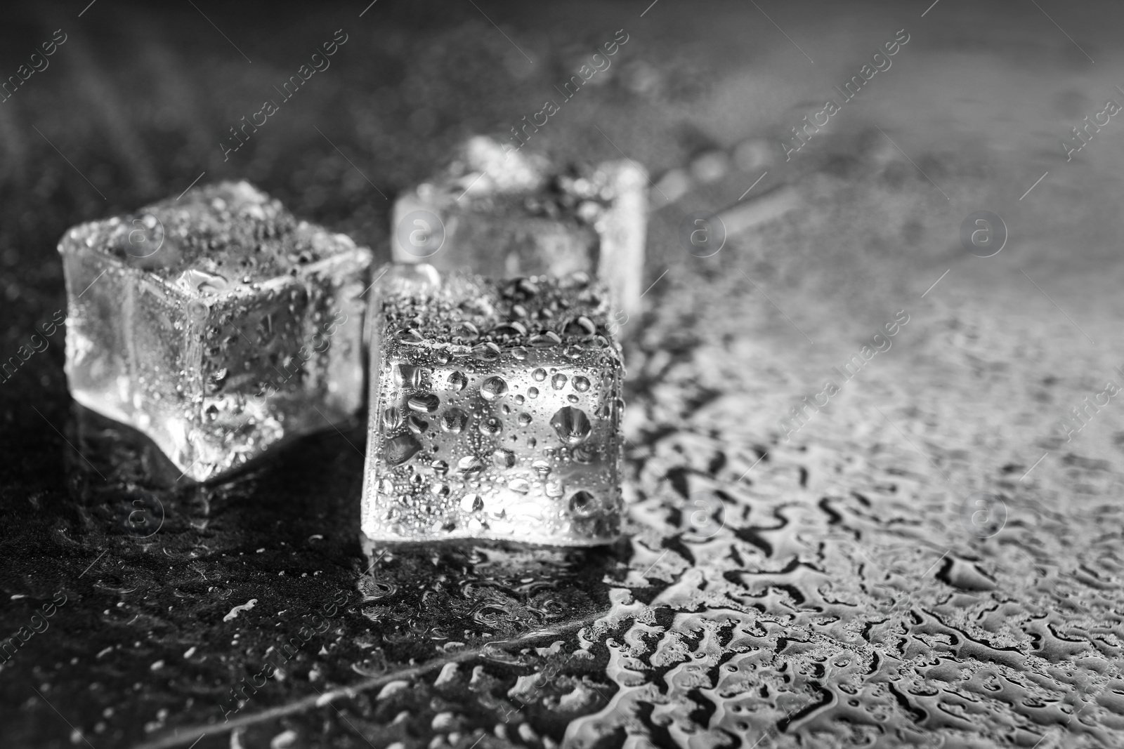 Photo of Crystal clear ice cubes on grey stone table, closeup. Space for text