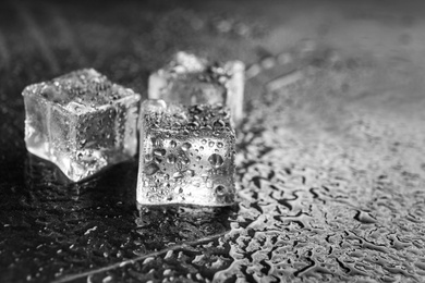 Photo of Crystal clear ice cubes on grey stone table, closeup. Space for text