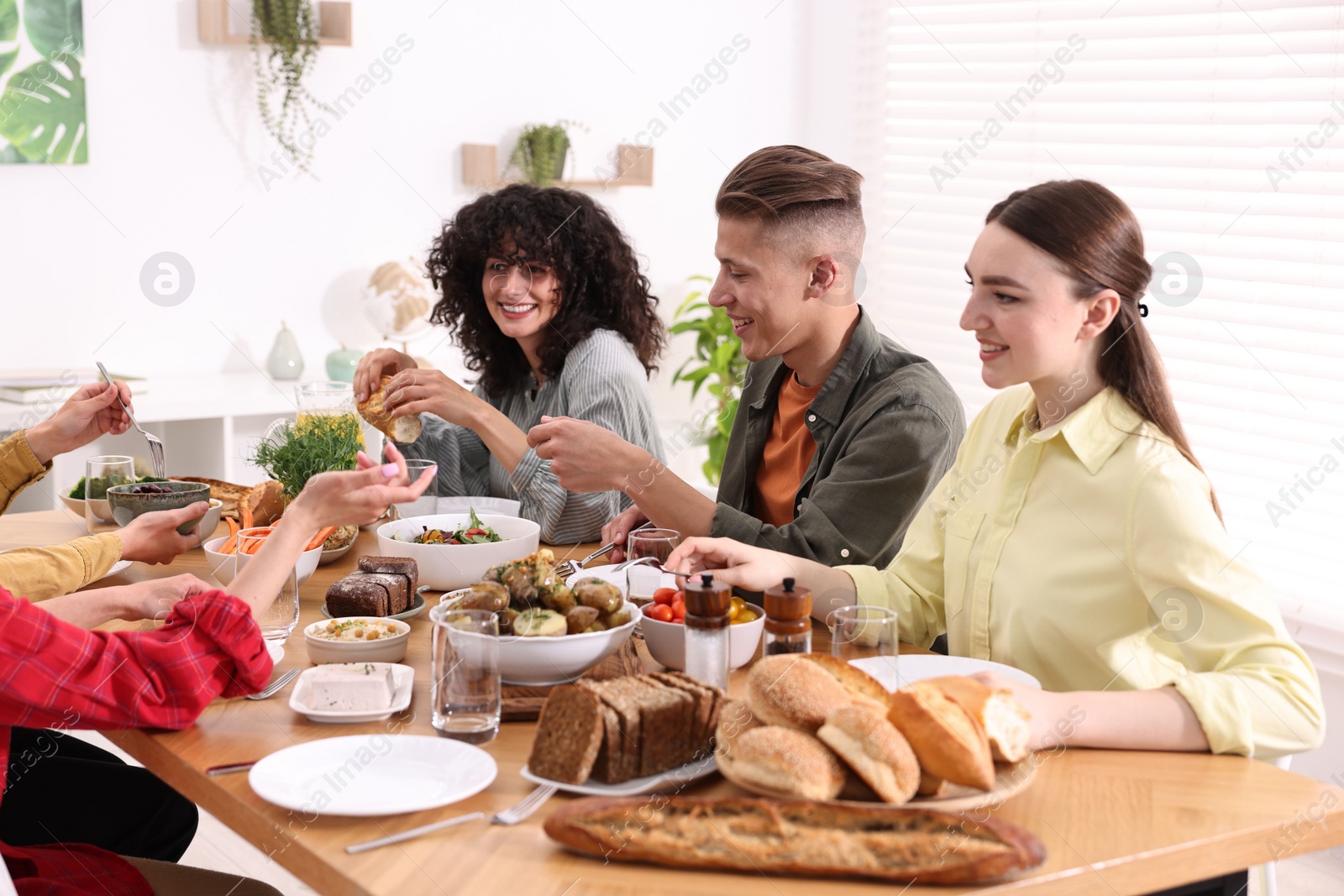 Photo of Friends eating vegetarian food at wooden table indoors