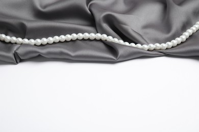 Photo of Beautiful pearls and grey silk on white background