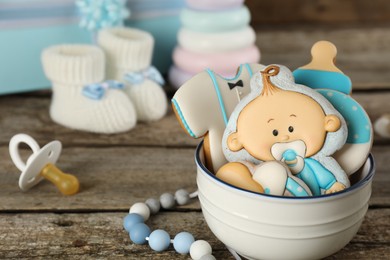 Photo of Cute tasty cookies of different shapes, toys and baby accessories on wooden table, closeup. Space for text