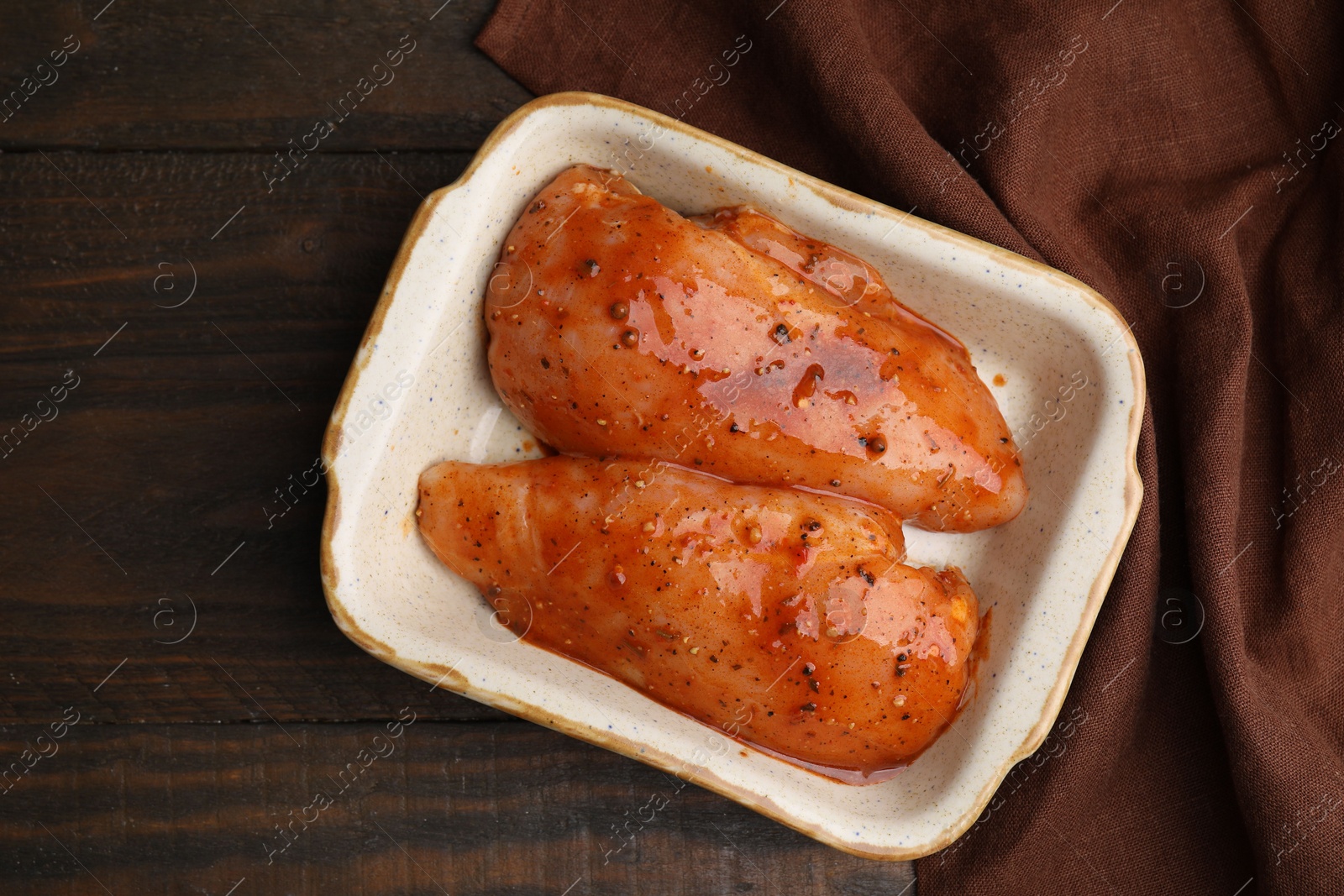 Photo of Raw marinated chicken fillets on wooden table, top view