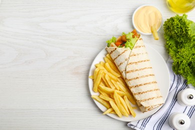 Delicious chicken shawarma and French fries served on white wooden table, flat lay. Space for text