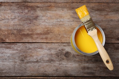Photo of Paint can and brush on wooden background, top view. Space for text