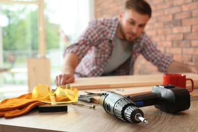 Photo of Young man working indoors, focus on electric screwdriver