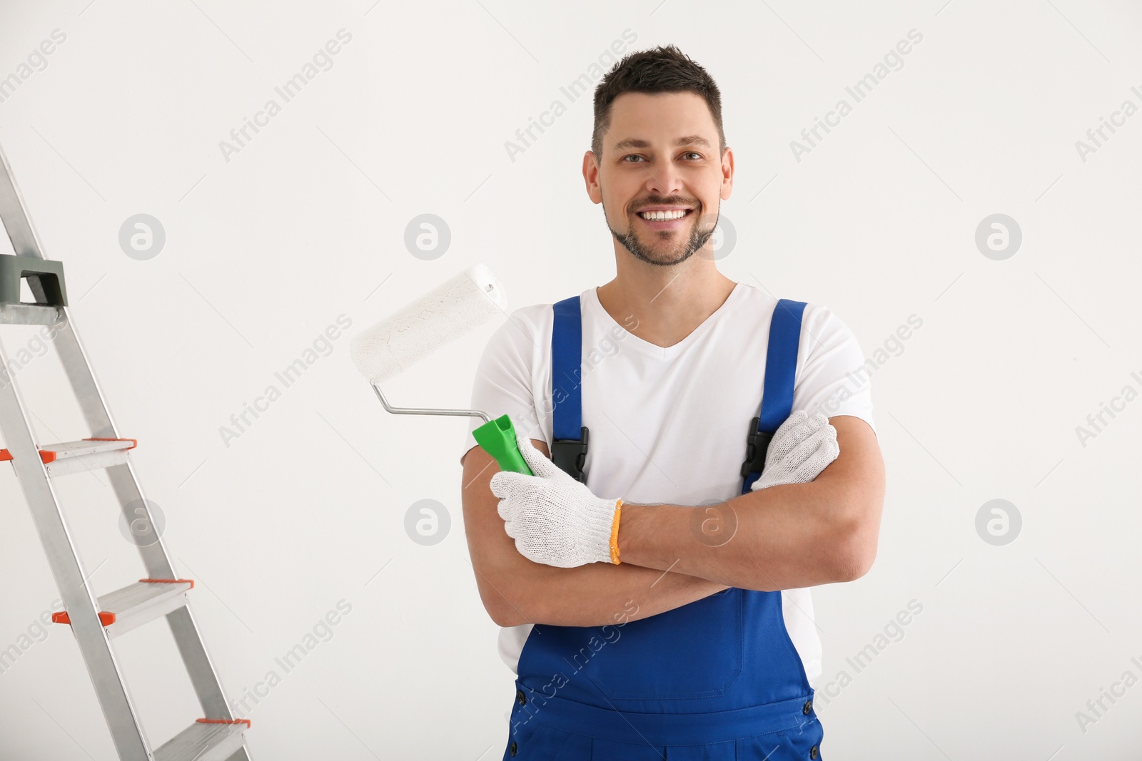 Photo of Man holding roller in empty room. Interior renovation