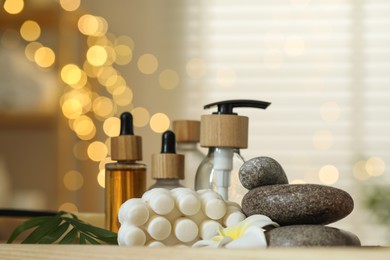 Photo of Composition with different spa products and plumeria flower on table indoors, bokeh effect