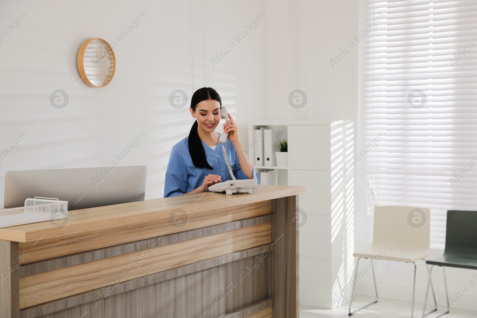 Photo of Receptionist talking on phone at countertop in hospital