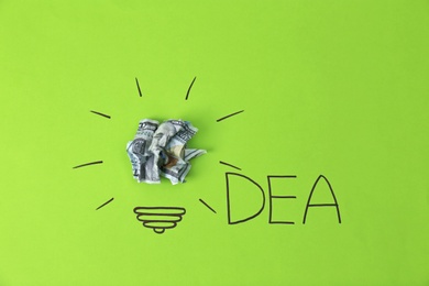 Photo of Composition with crumpled banknote, drawing of lamp bulb and word IDEA on color background. Creative concept