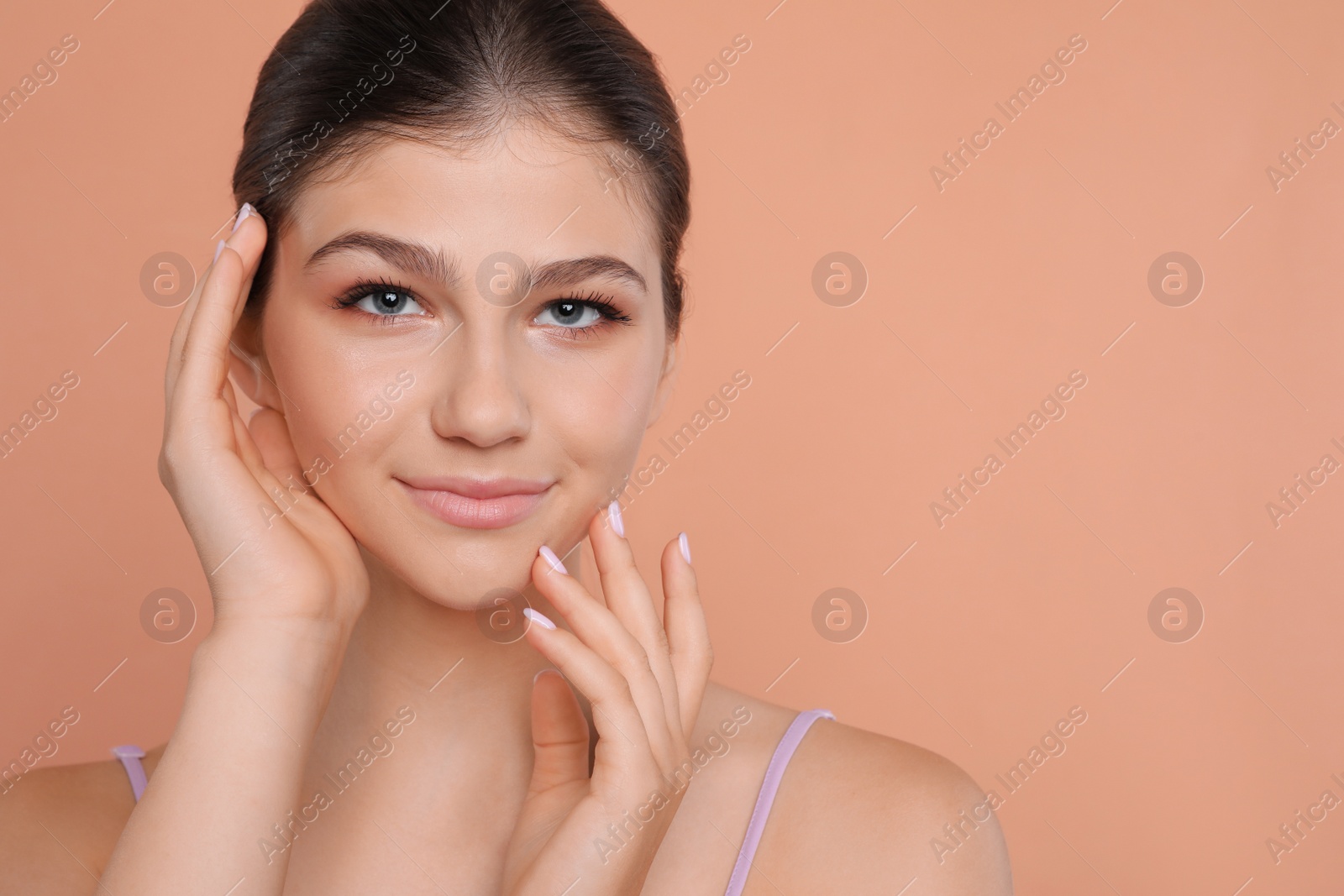 Photo of Pretty girl on pale coral background, space for text. Beautiful face with perfect smooth skin