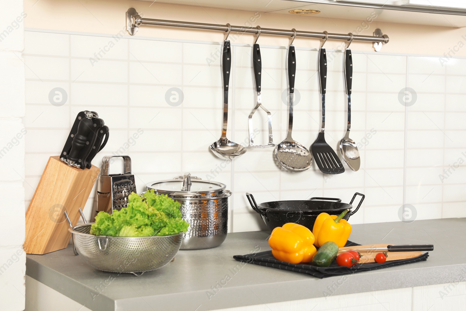 Photo of Set of clean cookware, utensils and products on table in modern kitchen