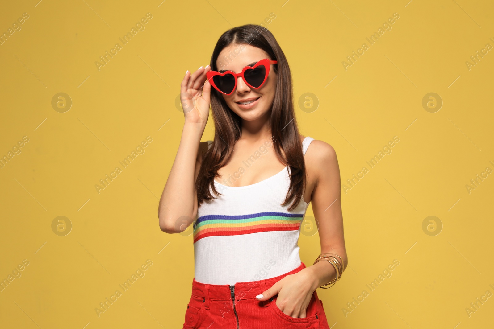 Photo of Portrait of beautiful young woman with heart shaped sunglasses on color background