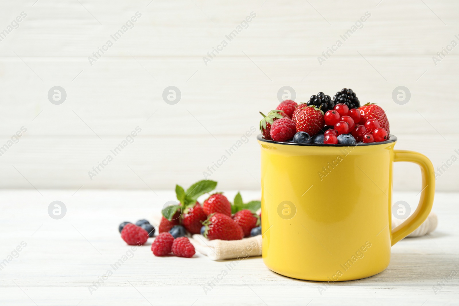 Photo of Mix of ripe berries on white wooden table. Space for text