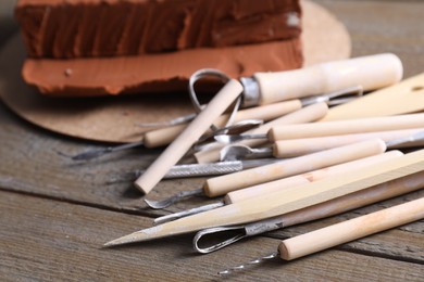 Clay and set of modeling tools on wooden table, closeup