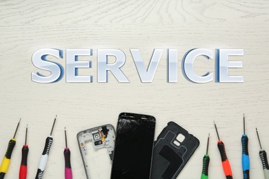 Parts of damaged smartphone and repair tool set on grey table, flat lay