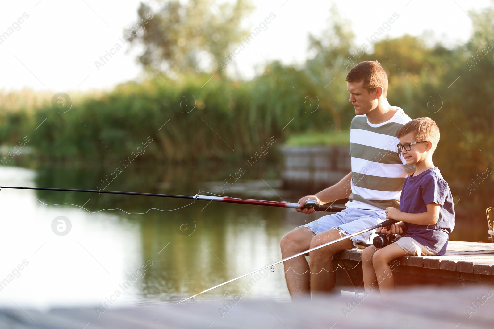 Photo of Dad and son fishing together on sunny day