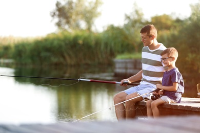 Dad and son fishing together on sunny day