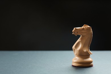 Photo of Wooden knight on table against dark background, space for text. Chess piece