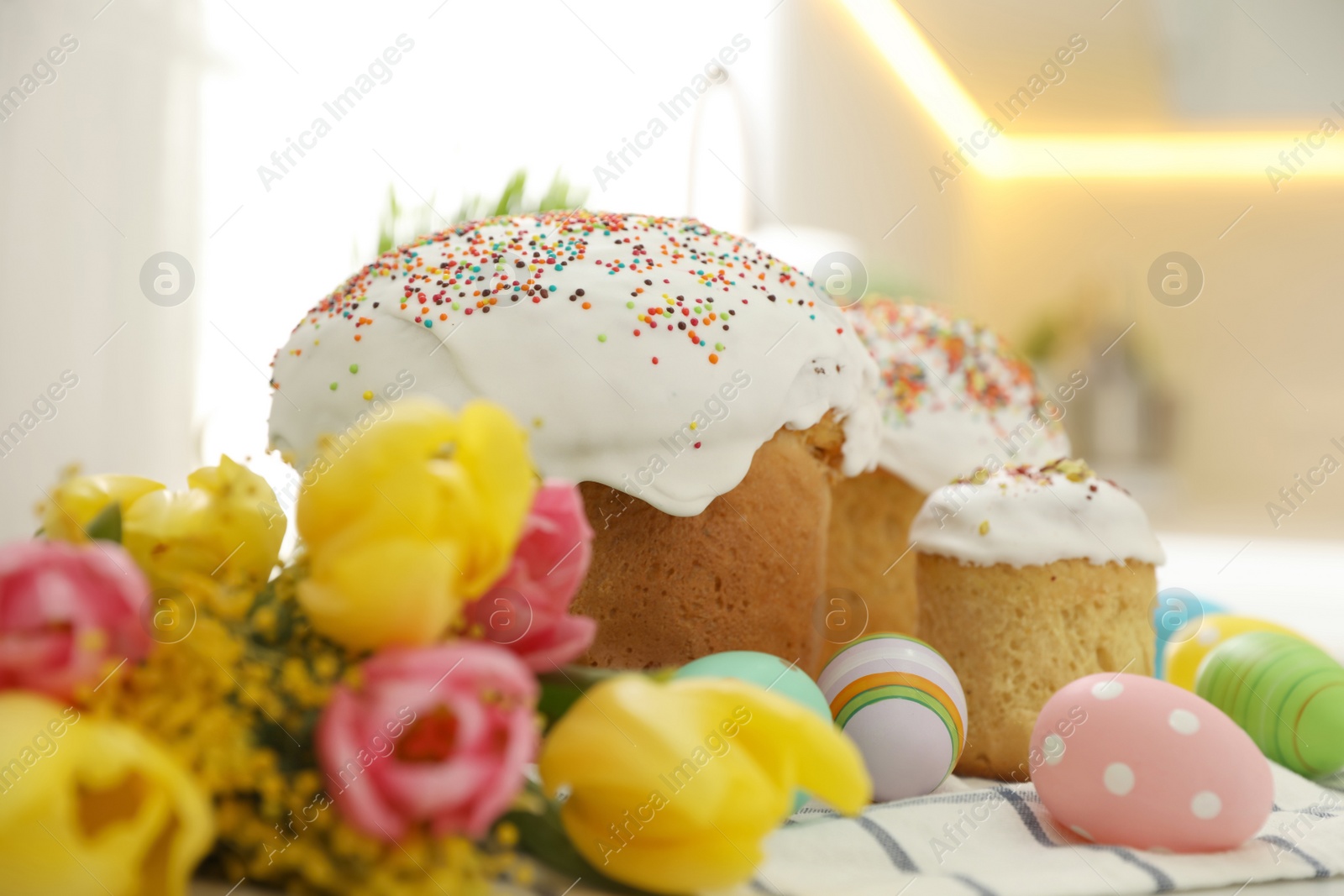 Photo of Traditional Easter cakes, flowers and dyed eggs on table, closeup