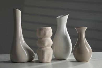 Photo of Different stylish vases on white marble table