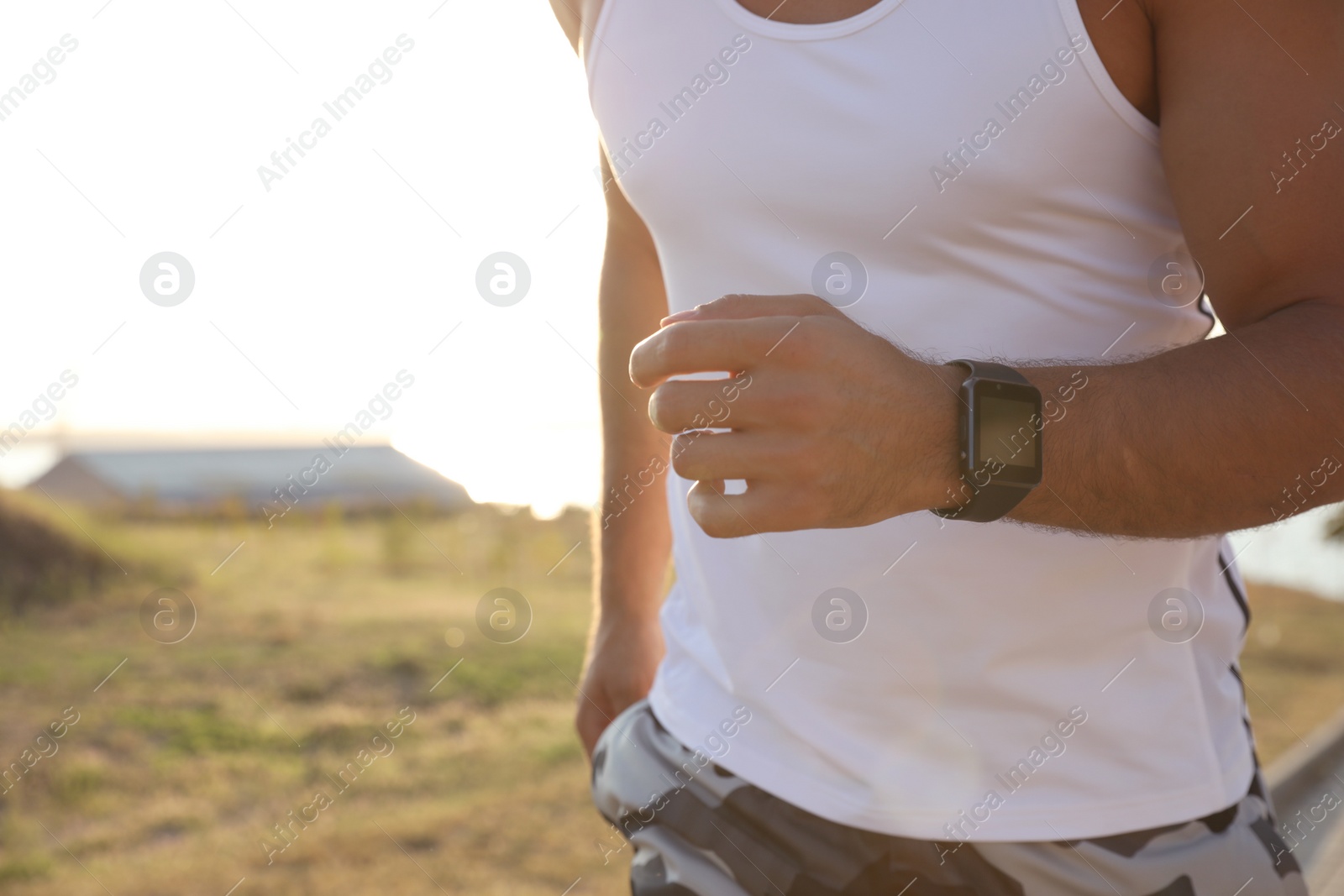 Photo of Man with fitness tracker running outdoors, closeup
