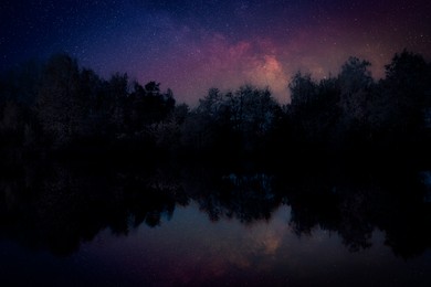 Amazing starry sky and trees reflecting in lake at night