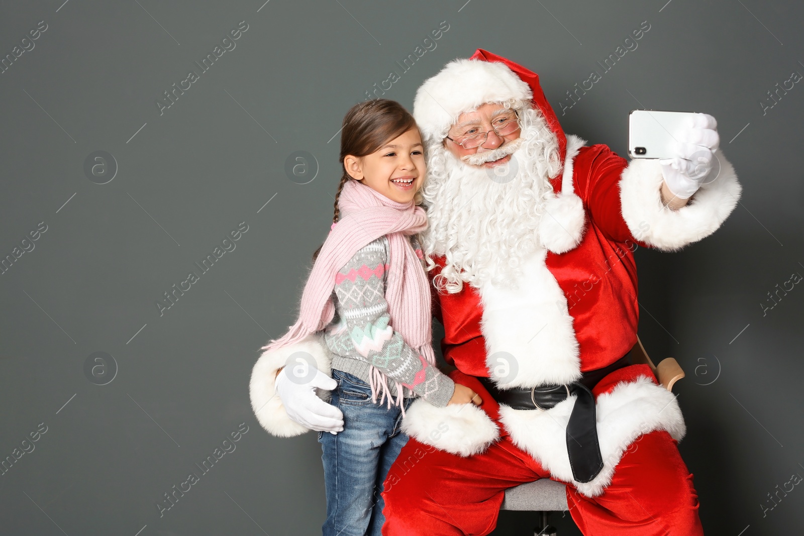 Photo of Authentic Santa Claus taking selfie with little girl on grey background