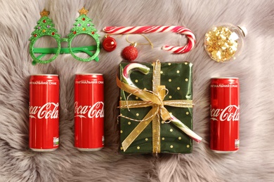 MYKOLAIV, UKRAINE - January 01, 2021: Flat lay composition with Coca-Cola cans and Christmas decorations on fur background