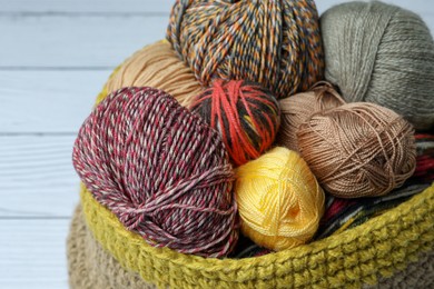 Photo of Soft woolen yarns on white wooden table, closeup