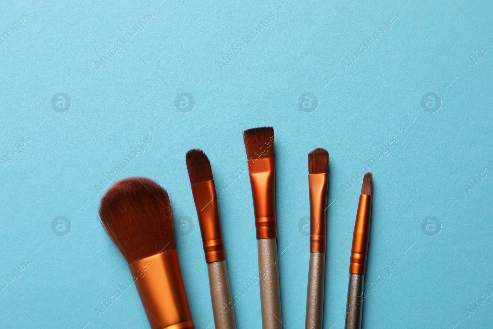 Photo of Set of makeup brushes on light blue background, flat lay. Space for text