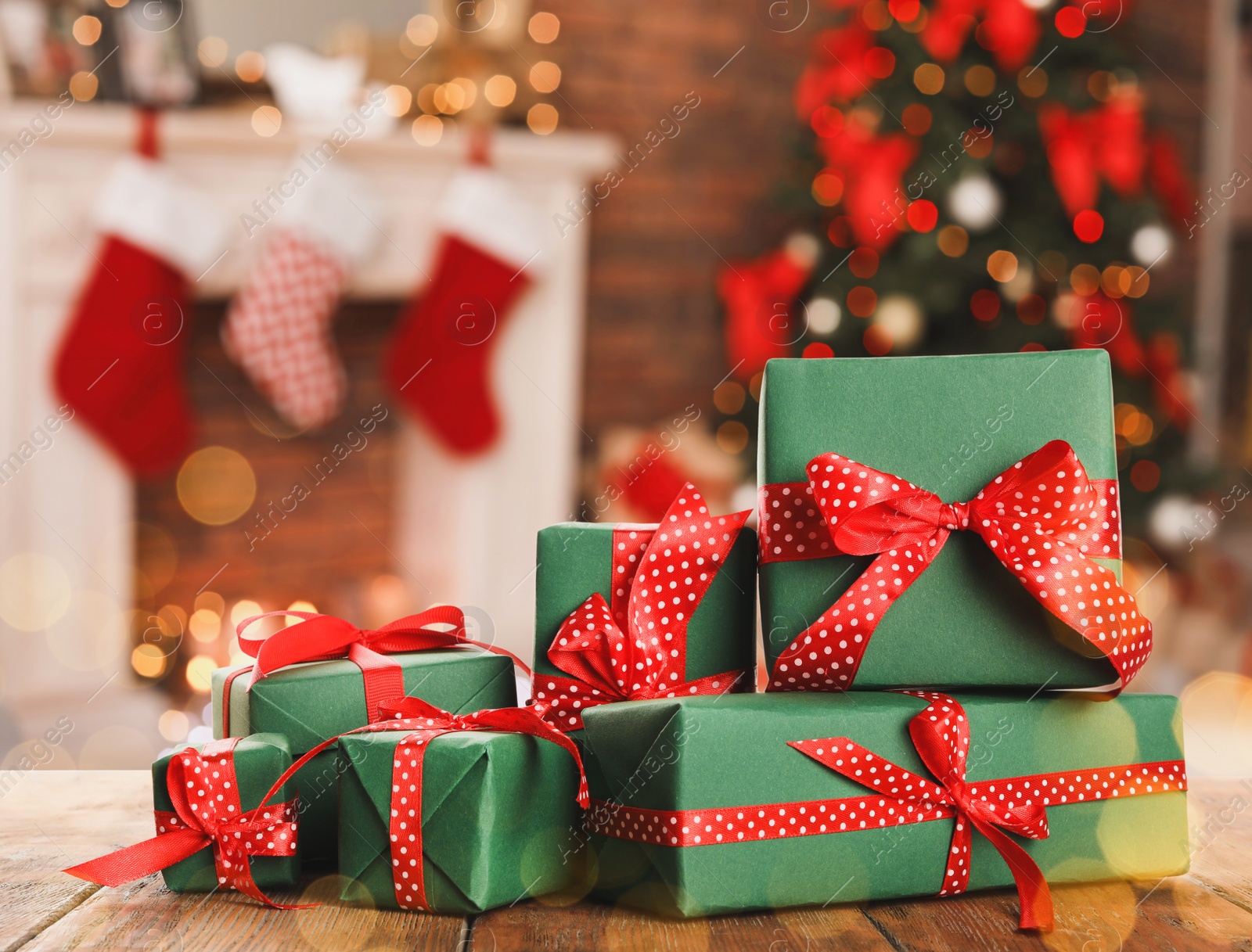 Image of Christmas gift boxes on wooden table in room, bokeh effect