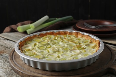 Photo of Tasty leek pie and raw stems on old wooden table